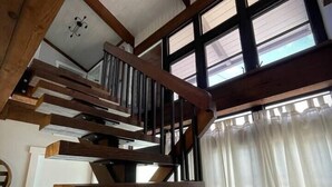 A wooden staircase with a modern chandelier, large windows, and a wooden table. - 04 Rustic meets beachy in Wilton Manors! (Wilton Manors)