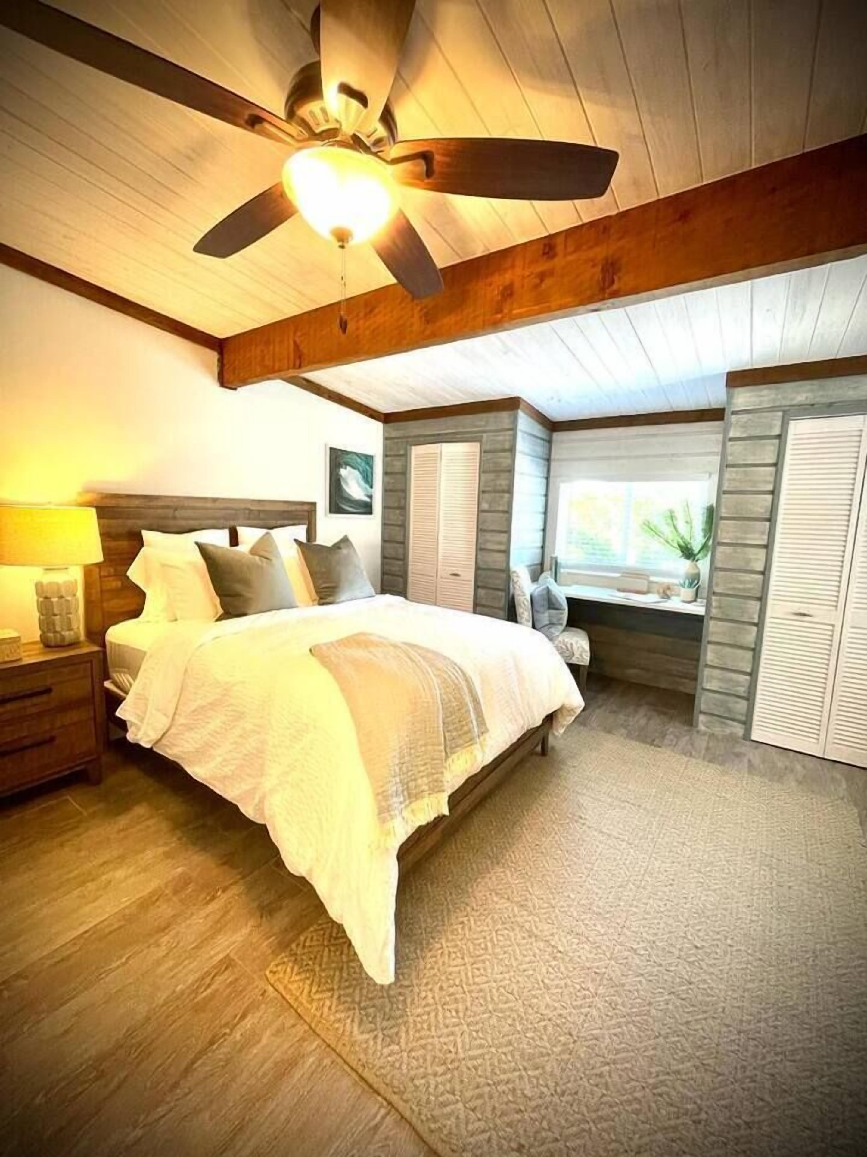 Een slaapkamer met een bed, nachtkastjes, een bureau en een raam.