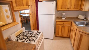 A compact kitchen with wooden cabinets, a gas stove, a refrigerator, a coffee maker, and a sink. - Webb Lake, Hackensack, Northern MN - 3 Bedroom, Sleeps 6 - Cabin #1 Blue Water (Hackensack)