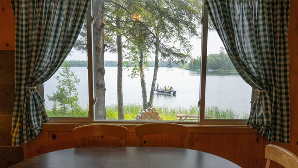 A dining area with a view of a lake and a boat. - Webb Lake, Hackensack, Northern MN - 3 Bedroom, Sleeps 6 - Cabin #1 Blue Water (Hackensack)