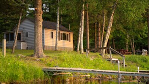 A cabin with a dock extending into a body of water, surrounded by trees and grassy areas. - Webb Lake, Hackensack, Northern MN - 3 Bedroom, Sleeps 6 - Cabin #1 Blue Water (Hackensack)