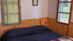 A bedroom with a bed, a window, and a wall with a framed picture. Text on the wall instructs guests to bring their own bedding and towels. - Webb Lake, Hackensack, Northern MN - 3 Bedroom, Sleeps 6 - Cabin #1 Blue Water (Hackensack)