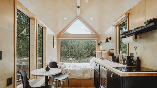 Une petite cabane moderne et fonctionnelle, comprenant une chambre, un coin cuisine et un espace repas.