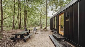 A cabin with a wooden deck, a picnic table, and a bench.