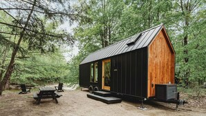 A cabin with a wooden exterior, a metal roof, and a small porch. - Lumen Nature Retreat | Cabin HYGGE-ASTRID (North Woodstock)