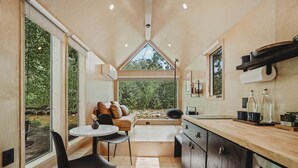 A compact kitchen with a dining area, large windows, and a view of the outdoors. - Lumen Nature Retreat | Cabin HYGGE-ASTRID (North Woodstock)