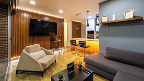 A modern living room with a sofa, a coffee table, and a TV mounted on the wall. - Stunning views from 25th-floor condo! El Poblado! (Medellín)