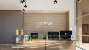A modern hotel reception area with a glass desk, a wooden wall with the hotel's name, and two decorative lamps. - Stunning views from 25th-floor condo! El Poblado! (Medellín)