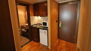Una cocina compacta con armarios de madera, un microondas y un refrigerador pequeño.