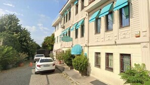 Un edificio de fachada clara, toldos azules y una calle adoquinada.