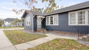 A residential house with a dark exterior, white trim, and a front porch.
