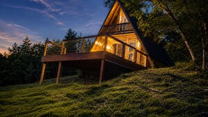 A wooden cabin with a balcony, surrounded by trees.