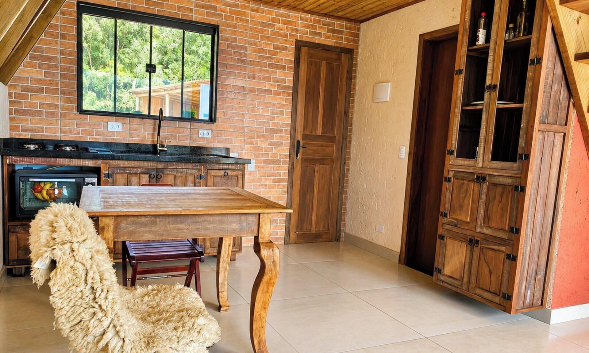 Una cocina con pared de ladrillo, armarios de madera, una mesa de comedor y una alfombra mullida.