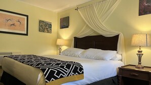 Une chambre d’hôtel avec un lit, une table de chevet, une lampe et des œuvres d’art accrochées aux murs.