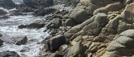 A rocky coastal landscape with large boulders and a view of the sea.