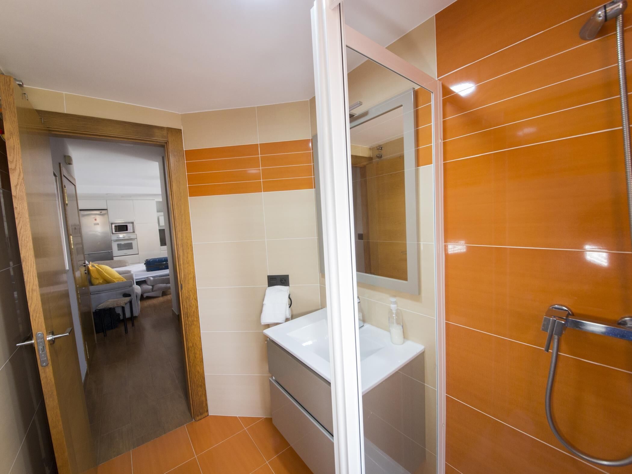 Un baño con ducha, lavamanos y espejo.