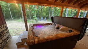 A hot tub with a wooden deck and a view of a forest. - Bobcat Corner, Hot Tub, Secluded, Pet Friendly (Logan)