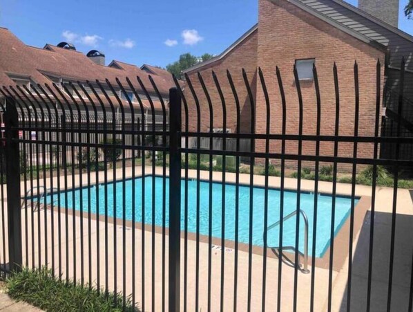Relax by the rectangular pool surrounded by a black fence.