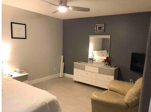 Relax in this serene bedroom with a comfortable bed, flat-screen TV, and stylish dresser.