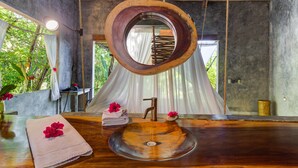 Une salle de bain avec un lavabo en bois, un miroir rond et une serviette à motifs floraux.