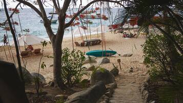 A beach pathway leading to the sea with a boat and beach chairs.