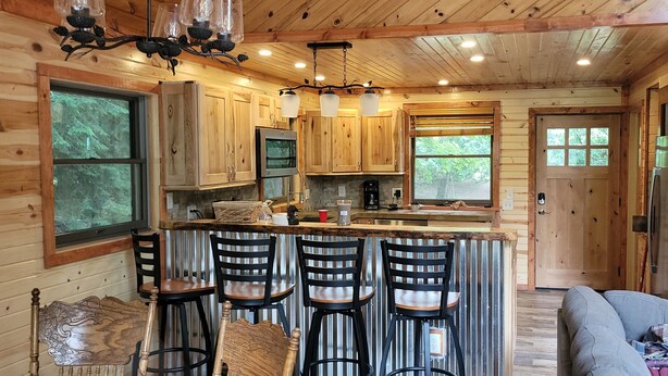 Interior de una cabaña de madera con cocina, barra y zona de estar.
