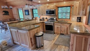 Cocina estilo cabaña de madera con una isla central, electrodomésticos de acero inoxidable y ventanas amplias.