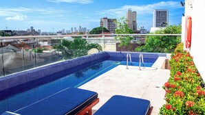 A rooftop pool with blue tiled edges, lounge chairs, and a cityscape view. - San Diego 974 Suites (Cartagena)