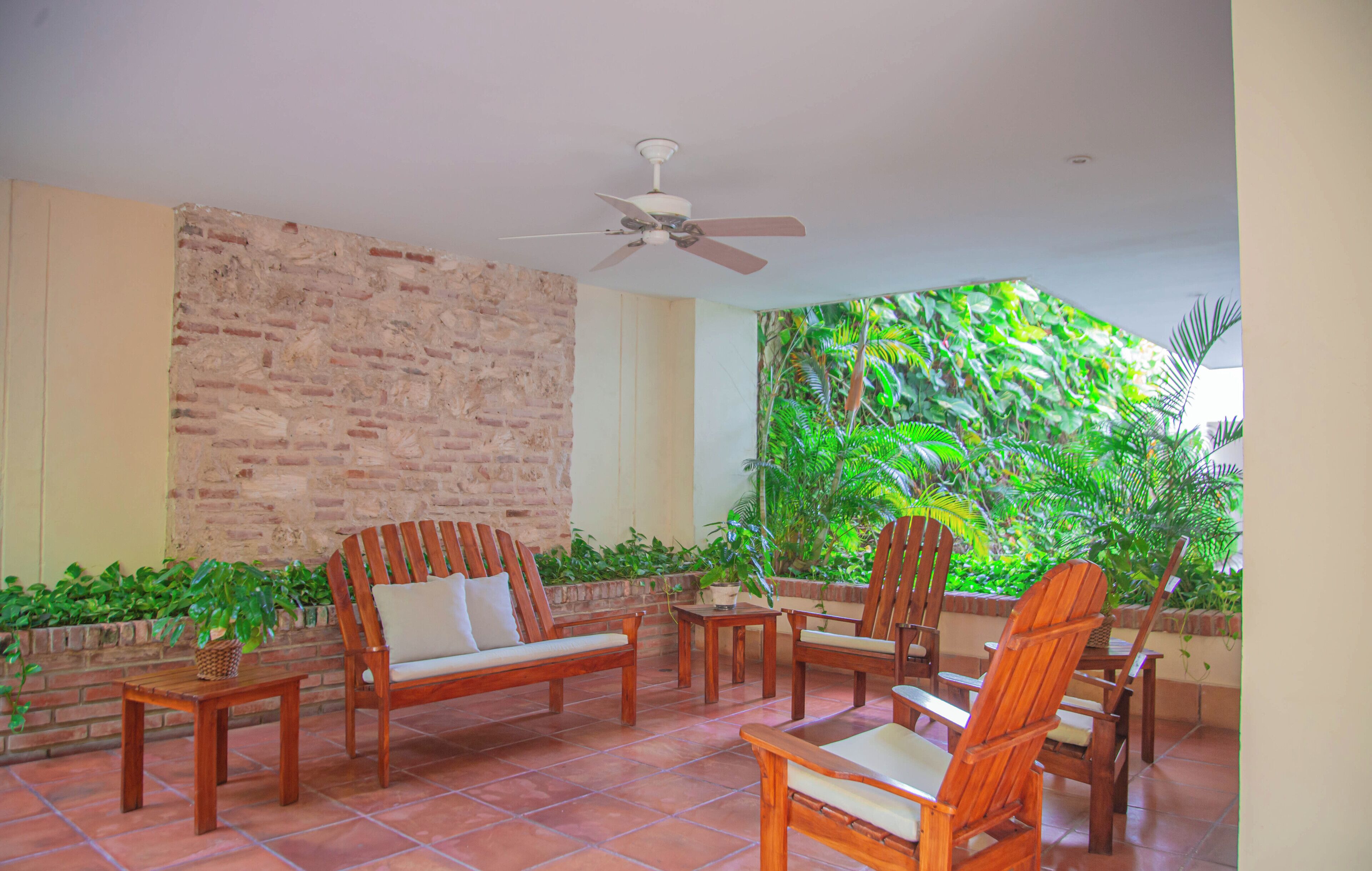 Un patio con mobili in legno, una ventola a soffitto e un muro in mattoni.