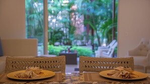 A dining area with wicker chairs and a table set for two, overlooking a lush garden. - San Diego 974 Suites (Cartagena)