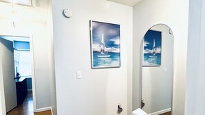Un corridoio con pavimento in legno, una porta bianca e un quadro appeso al muro raffigurante una barca a vela.