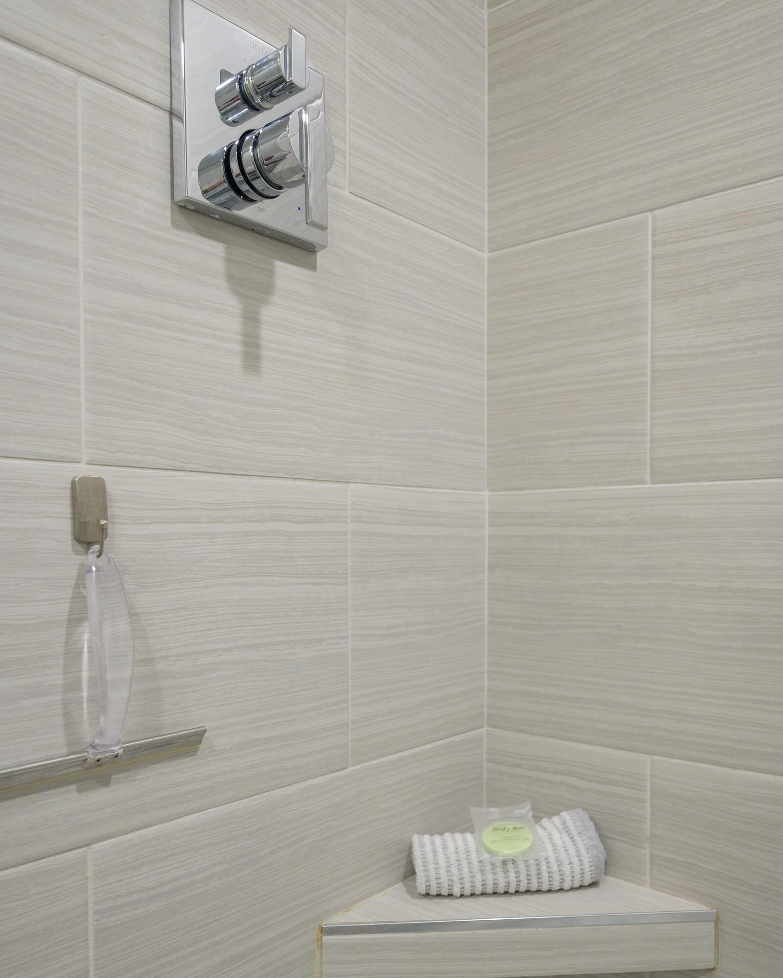 Un baño moderno con zona de ducha, toallero y estante con artículos de aseo.