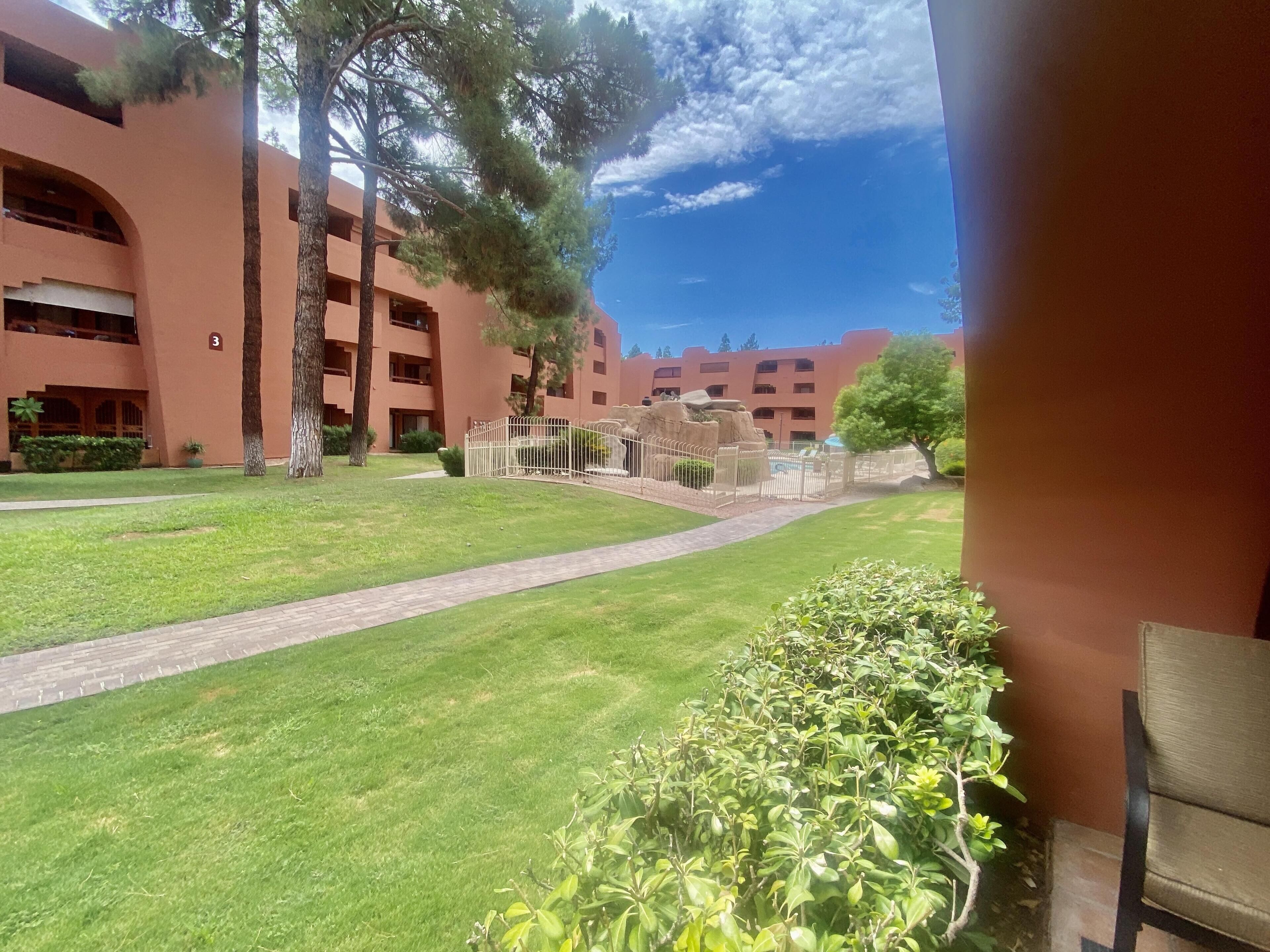 A courtyard with a pathway, a pool area, and a building with multiple balconies.