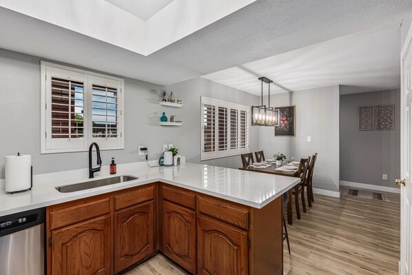 A modern kitchen with a large island, wooden cabinets, and a built-in dishwasher. - CASA T'OSO-Anasazi Village-1st floor pet friendly (Phoenix)