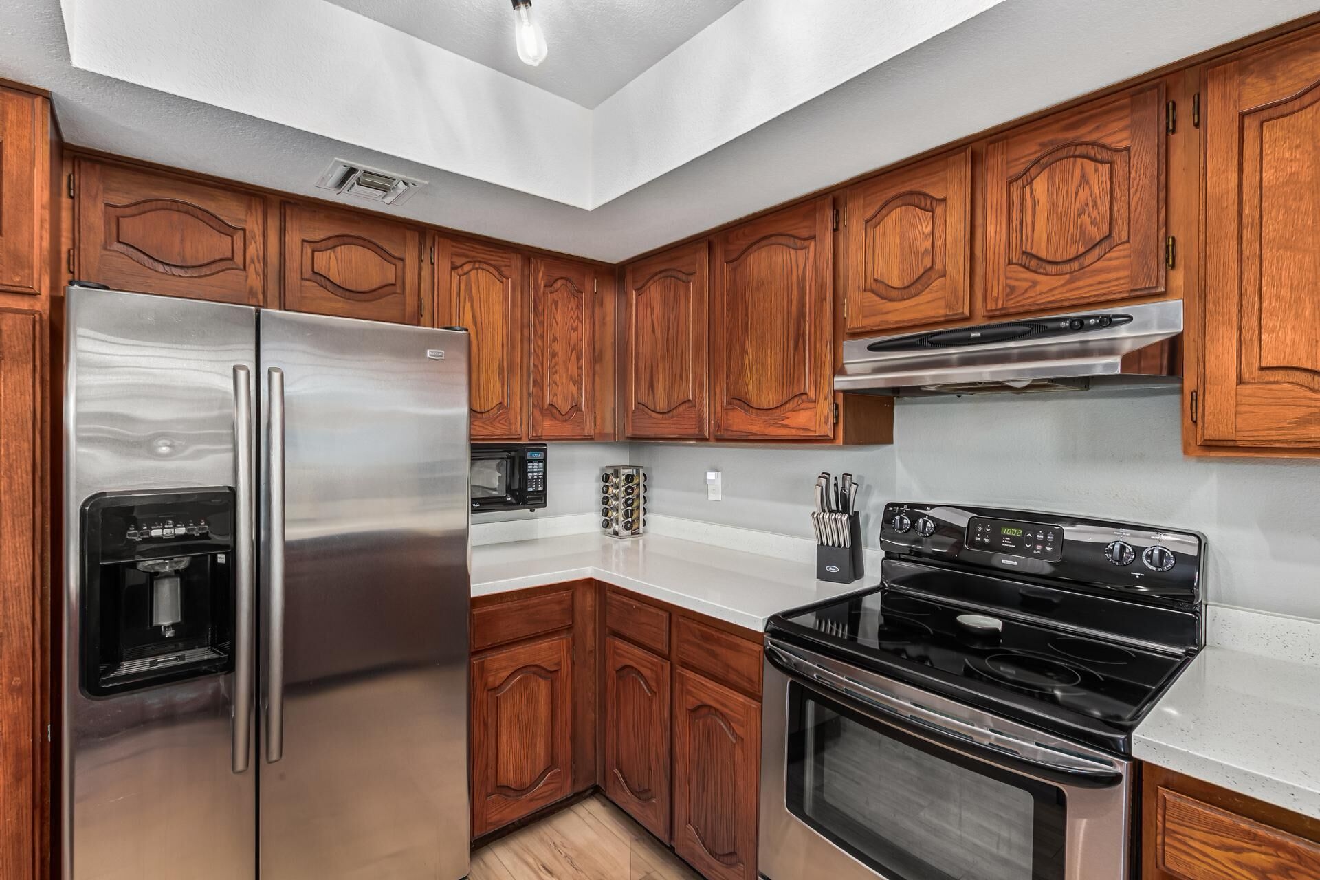 Una cocina moderna con armarios de madera, electrodomésticos de acero inoxidable y una estufa negra.