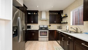 Een moderne keuken met donkere houten kastjes, roestvrijstalen apparatuur en een backsplash van baksteen.