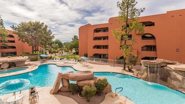 A hotel with a large outdoor swimming pool, multiple balconies, and a landscaped area with trees and rocks. - CASA AVENTURA - Anasazi Village - Views (Phoenix)