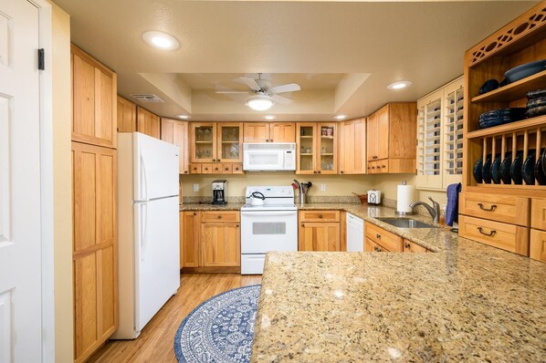 A kitchen with wooden cabinets, a white refrigerator, a microwave, a stove, and a sink. - CASA MONTANA - Anasazi Village - 2nd Floor View (Phoenix)