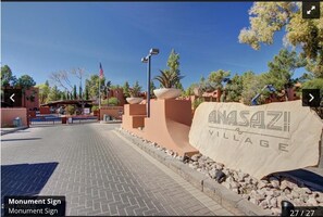 Ein gepflasterter Eingangsbereich mit einem Schild, auf dem 'ANASAZI VILLAGE' steht, und einer Flagge.