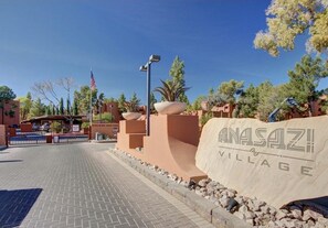 A paved entrance with a sign reading "ANASAZI VILLAGE" and a flag.