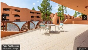 An outdoor terrace with a table and chairs, surrounded by a railing and overlooking a building with multiple balconies. - CASA ANA - Anasazi Village - Updated unit, pool view. (Phoenix)