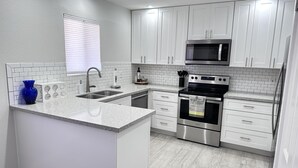 A modern kitchen with white cabinets, a stainless steel oven, and a microwave. - CASA ANA - Anasazi Village - Updated unit, pool view. (Phoenix)