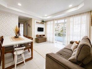 Uma sala de estar moderna com área de jantar, televisão de tela plana e varanda com vista para a cidade.