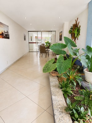 A spacious indoor area with a tiled floor, a seating area with chairs, and potted plants. - Aconchegante Apto Prainha Arraial- RJ (Arraial do Cabo)