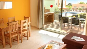A bright living room with a glass table, wooden chairs, a red sofa, and a view of a pool and buildings outside. - Large houses with terrace and pool for 6 people. Ref.via augusta-6 (Creixell)