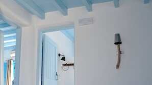 A bedroom with a bed, a door, and a wall-mounted lamp. - Belogna Ikons (Naxos)
