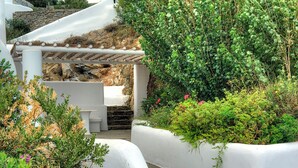 A white outdoor seating area with stone steps leading up to a white structure. - Belogna Ikons (Naxos)
