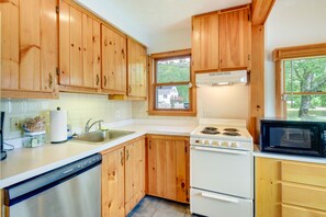 A kitchen with wooden cabinets, a white stove, a dishwasher, and a microwave.