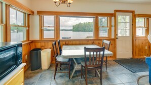 Une cuisine avec vue sur un lac, des murs en bois, une table à manger avec des chaises, un four à micro-ondes et une poubelle.