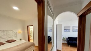 A bedroom with a bed, a bedside table, a mirror, and a door leading to another room. - Las Canteras View Home (Las Palmas de Gran Canaria)
